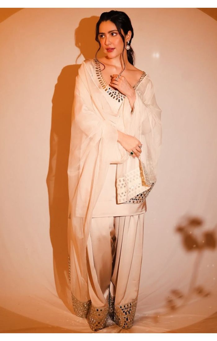 Close-up of woman in an ivory sharara set highlighting the mirror embroidery on the neckline and soft dupatta.