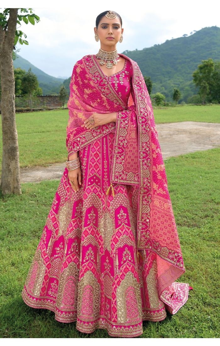 A royal pink Banarasi lehenga with gold zari work and intricate embroidery, perfect for Indian weddings and festive celebrations.