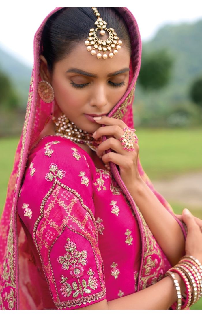 A royal pink Banarasi lehenga with gold zari work and intricate embroidery, perfect for Indian weddings and festive celebrations.