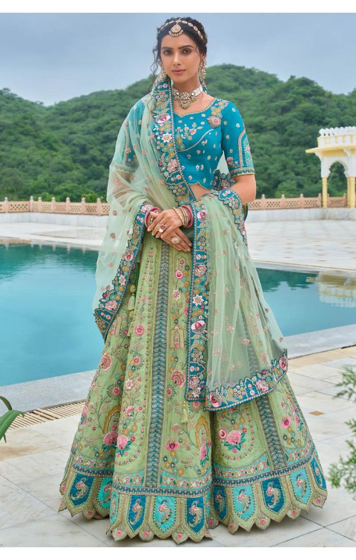 Teal blue and mint green embroidered lehenga choli with intricate floral motifs, designed for weddings and grand celebrations, paired with a net dupatta featuring detailed border work.
