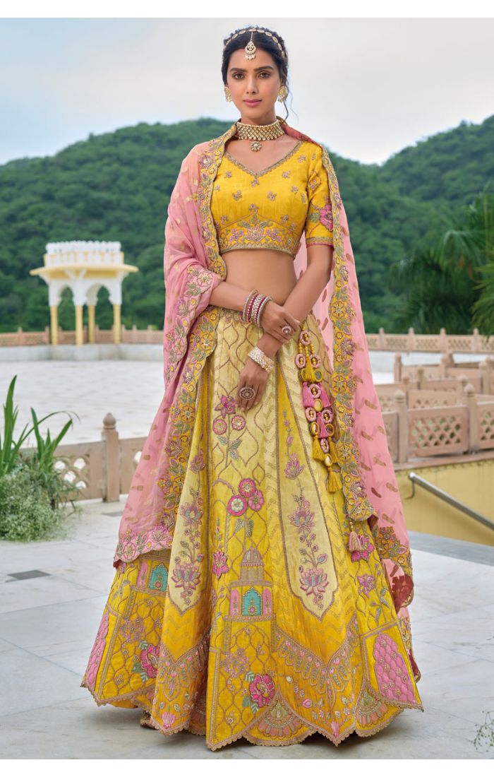 Yellow embroidered lehenga choli with intricate floral motifs, paired with a pink dupatta, ideal for Haldi ceremonies and wedding festivities.